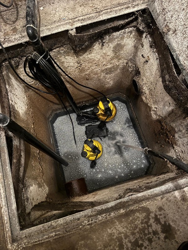 Pumpensumpf mit zwei gelben Tauchpumpen in einem Kellerschacht